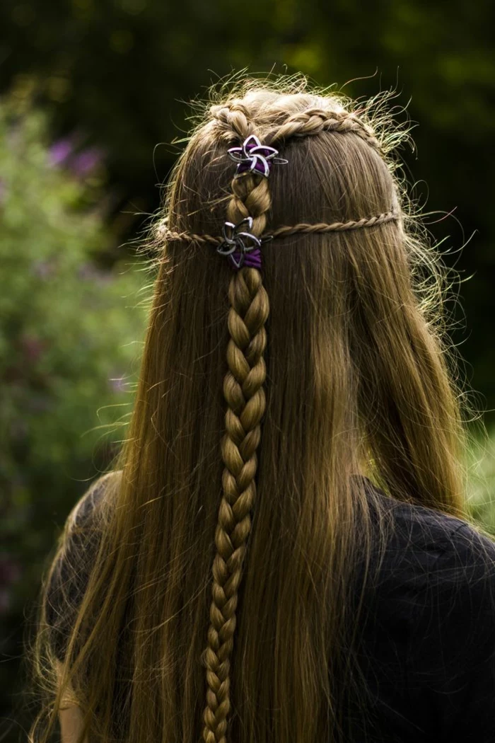 medieval braids, long straight dark blonde hair, with several small braids at the top, coming together in a bigger braid in the middle, and decorated with purple hairbands, and silver flowers