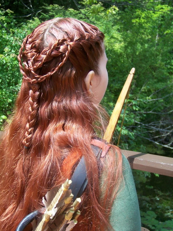 medieval hairstyles, girl holding wooden bow and arrows, with red partially braided hair, forming a complex pattern at the back of her head