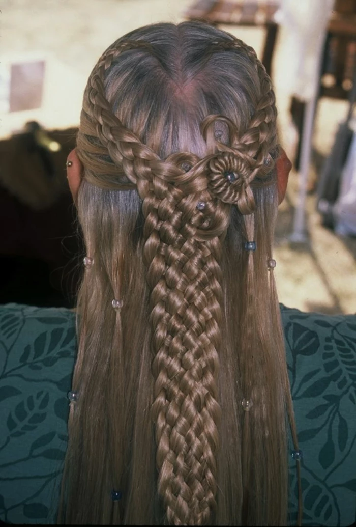 medieval hairstyles, dark brown hair, partially woven in several braids from each side, joining together in the middle, to form one thick braid, clear and green beads in hair, green top with leaf pattern