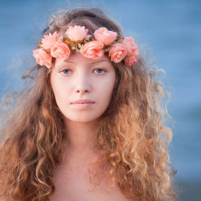 renaissance hairstyles, messy curly hair, and a wreath of pink roses, worn by young woman, with blue eyes