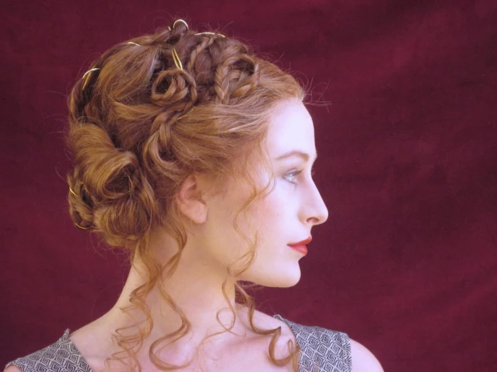 unusual hairstyle for ginger hair, made up of curls, twists and braids, worn by woman with red lipstick, looking to one side