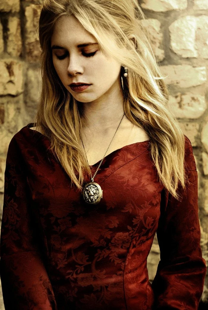 medieval times hair, young woman with red lipstick and dress, with floral embroidery, wavy blonde hair, and a chunky locket