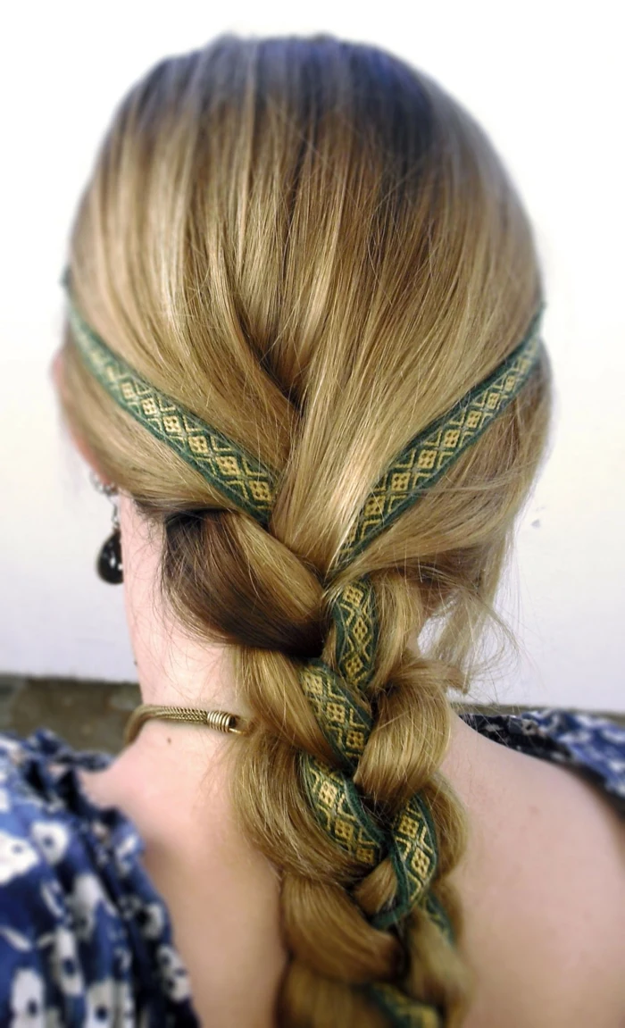 elizabethan hairstyles, blonde hair woven in a simple braid, with a green and gold-embroidered ribbon running through it