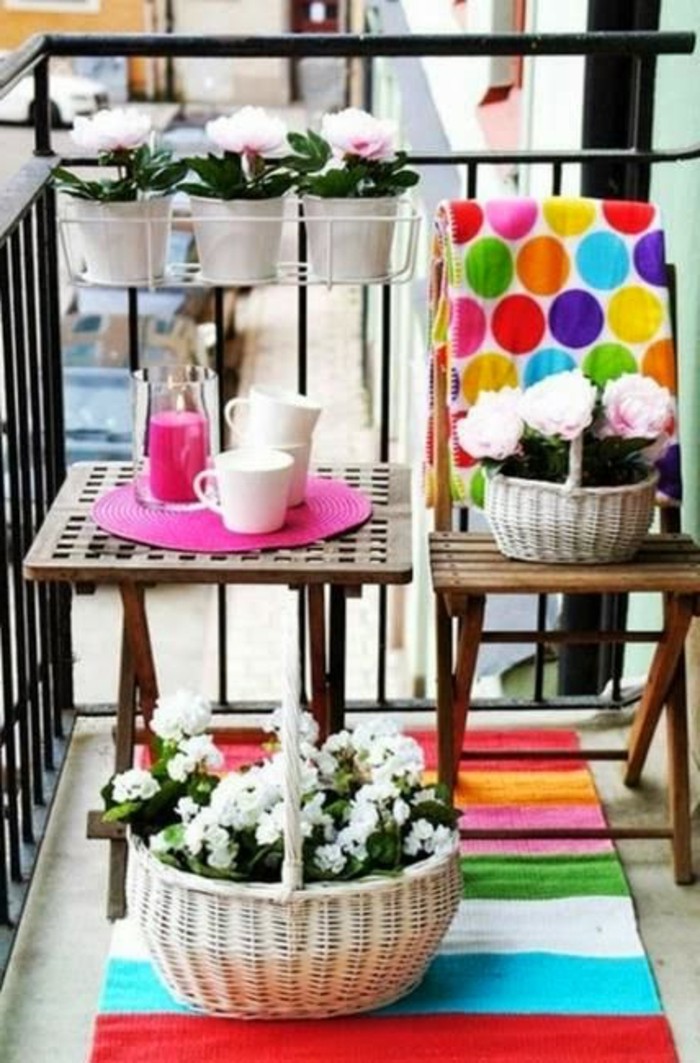 small square wooden table, near wooden chair, porch ideas, several potted plants in pots and baskets, bright table decorations, and multicolored blanket