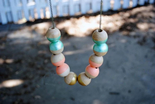 several wooden beads, half colored in turquoise, coral pink or gold, stringed on a chain