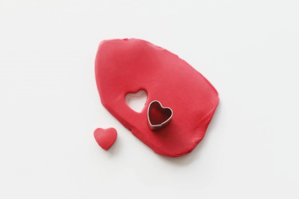 modelling clay in red, with a heart-shapped cutter, small heart-shaped hole, art and craft ideas, red clay heart shape nearby
