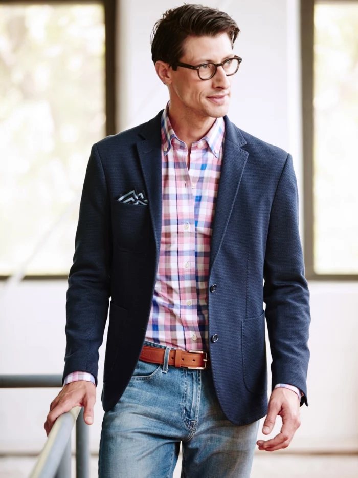 working professional with glasses, wearing plaid shirt, navy blazer with pocket handkerchief, and pale business casual jeans, with brown leather belt