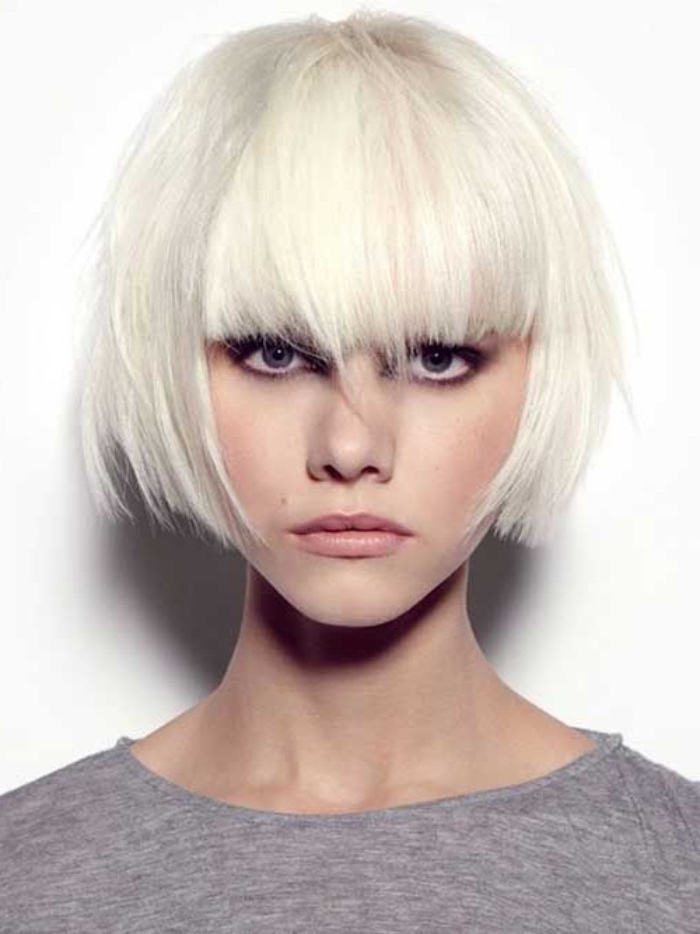 bob haircut on platinum blonde hair, with long thick bangs, worn by woman in grey top