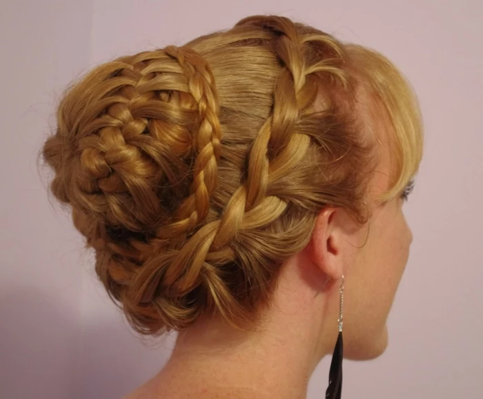 renaissance braids, braided blonde hair, with several layers of braids, forming a bun at the back, black feather earrings