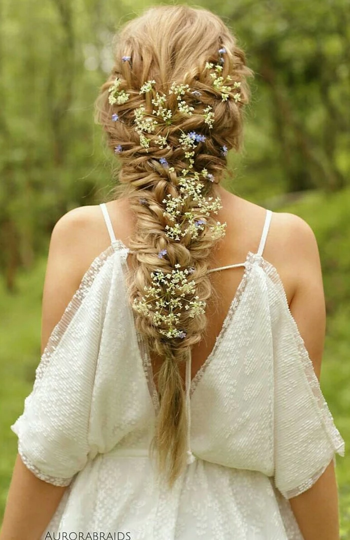 renaissance braids, long blonde messy braid, decorated with lots of tiny white and blue flowers, worn by woman in white off-shoulder lace dress