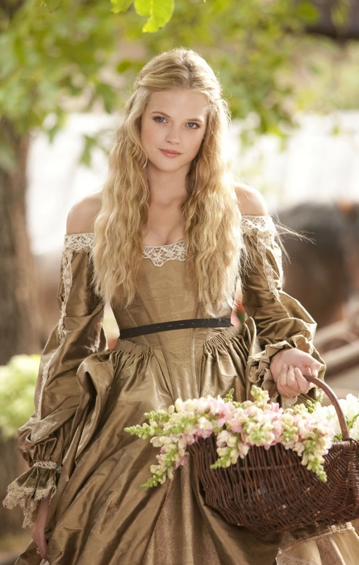 renaissance hairstyles, smiling girl with long, wavy blonde hair, partially tied back, wearing pale brown renaissance dress, and carrying a basket with flowers