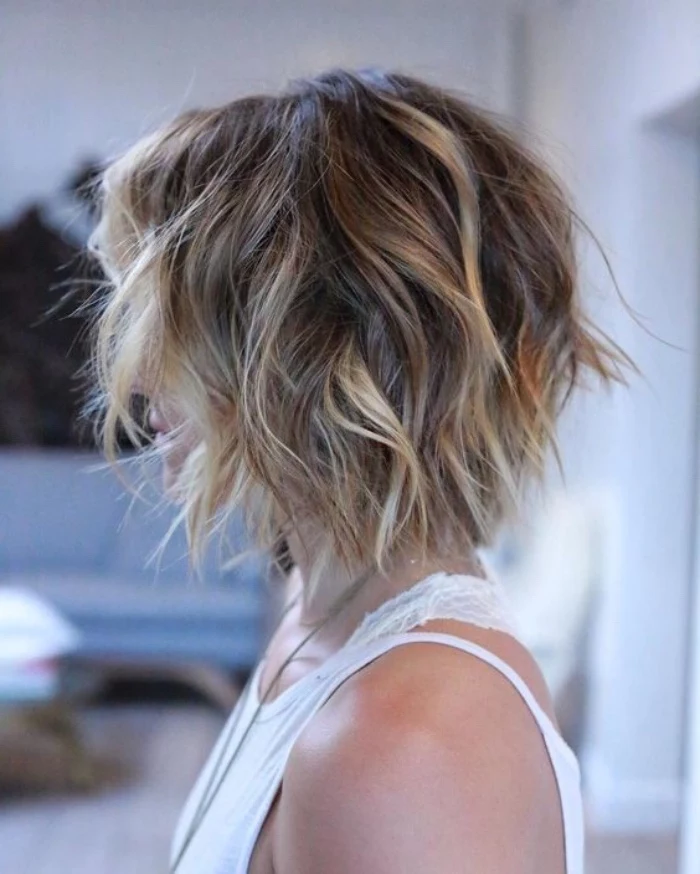 messy curly hair, dark blonde with lighter highlights, short bob haircuts, worn by woman in white tank top