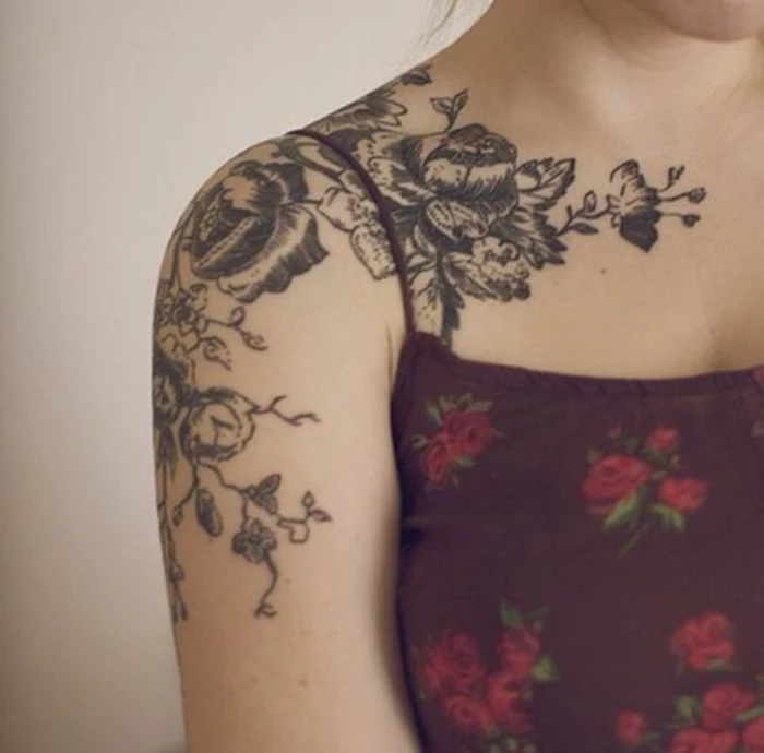 shoulder flower tattoos, woman in purple strappy top, with elaborate floral shoulder tattoo, made in black ink, going down her arm, and across her collar bone 