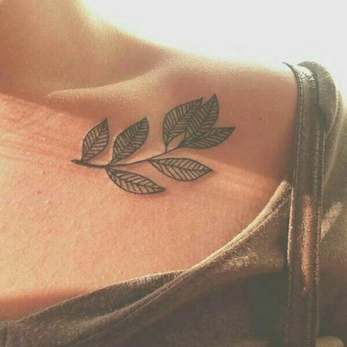 shoulder flower tattoos, simple tattoo of a leafy plant, made with black ink, on a woman's collar bone, near her shoulder