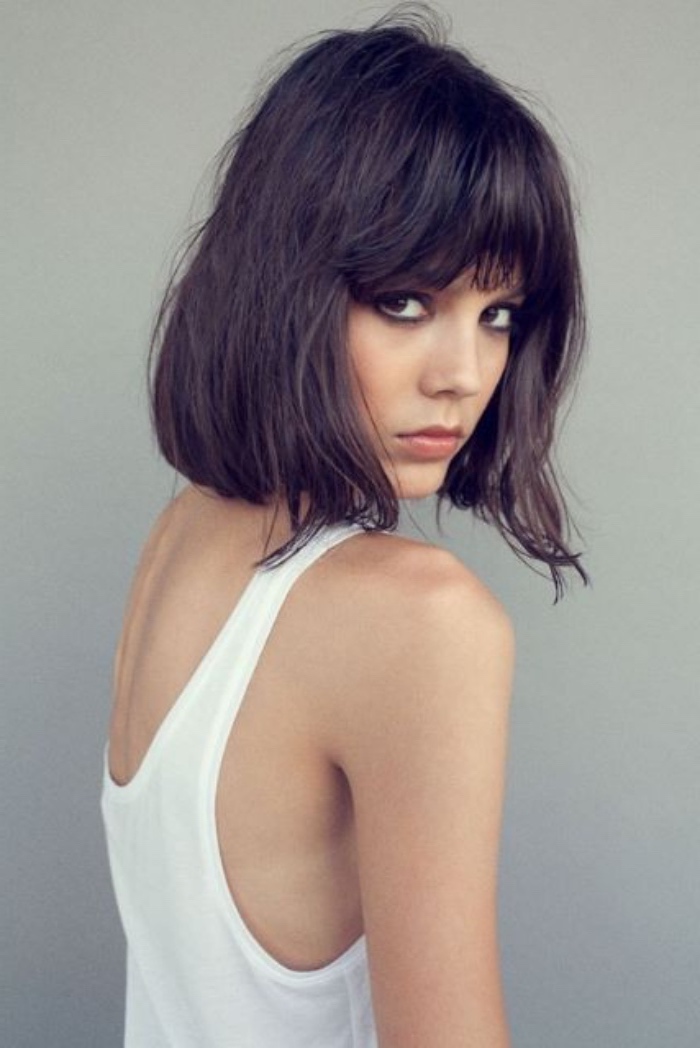 short bob haircuts, slim woman in white tank top, wearing messy dark hair with shaggy bangs