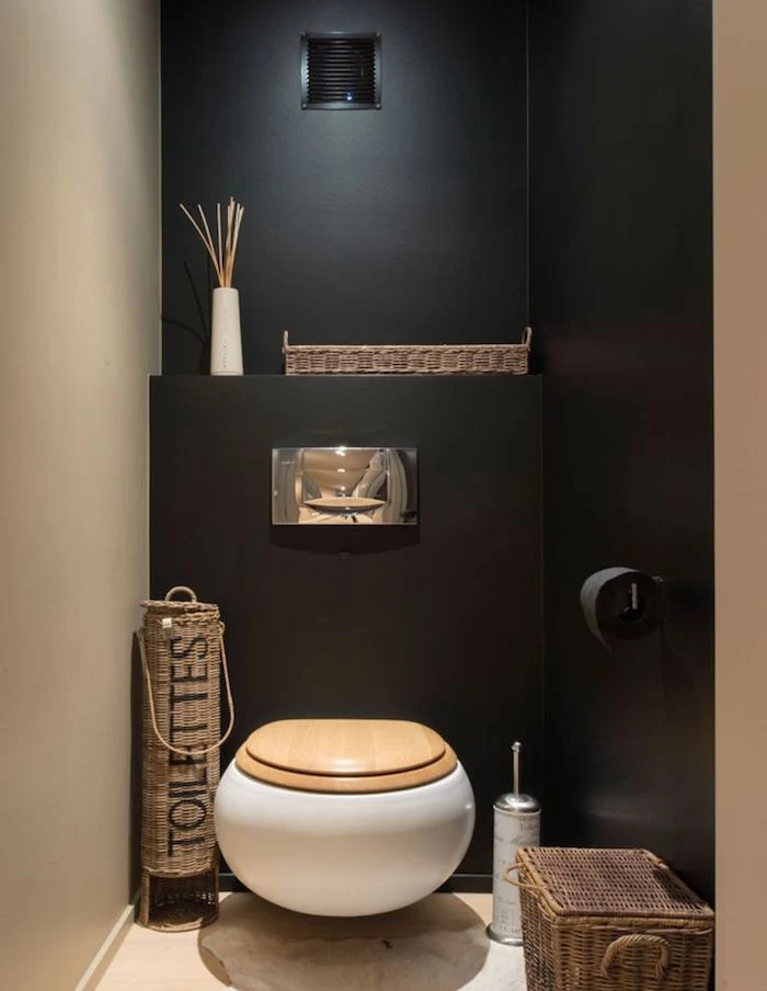 bathroom remodel, toilet with cream and black walls, containing oval white toilet seat with wooden lid, various whicker containers, black toilet paper