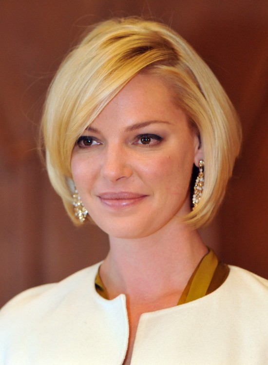 pageboy haircut with side-parting, worn by smiling blonde woman, dressed in white cardigan