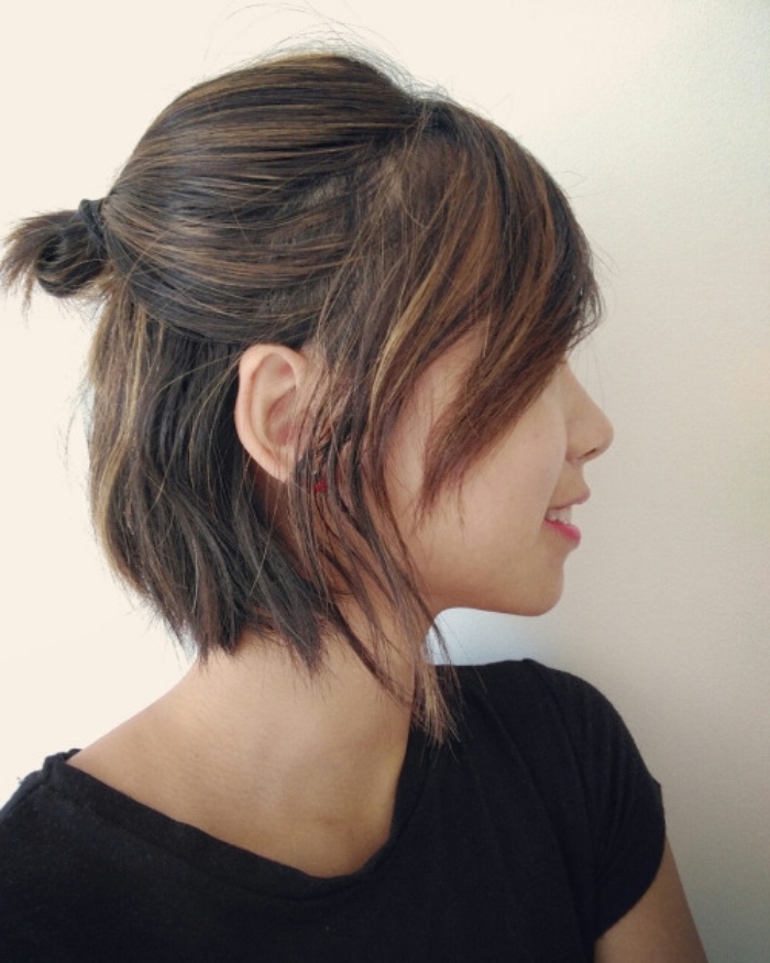 short bob, partially tied in a small bun at the back, worn by smiling young woman, wearing black t-shirt