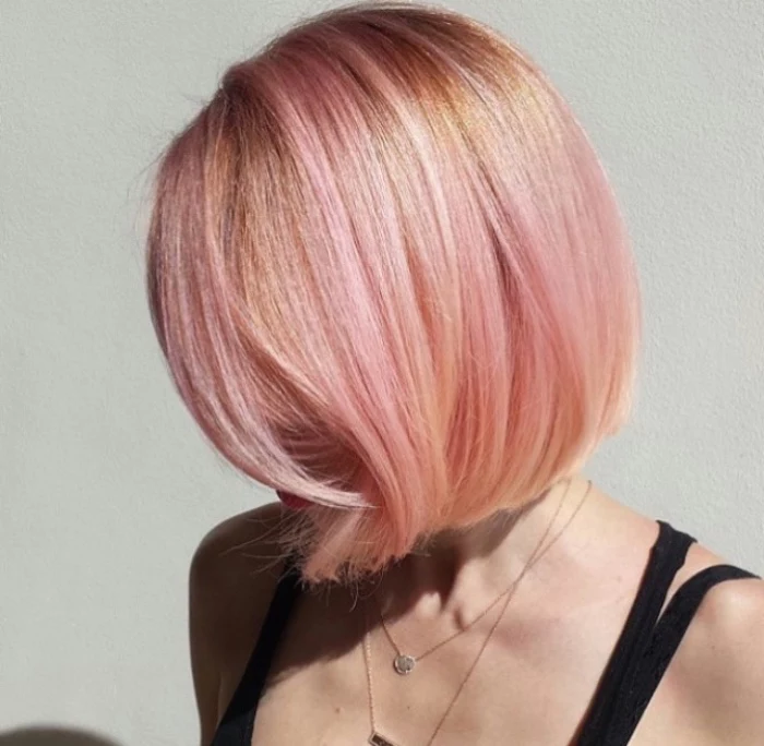 short hair colored in pink and pale orange, bob haircut, worn by woman in black strappy top