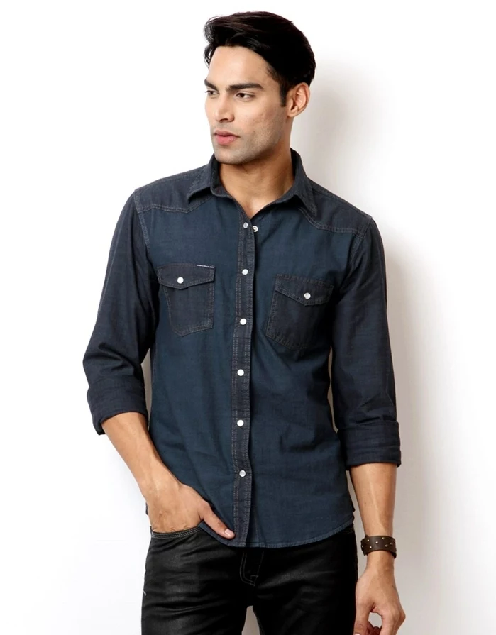 business casual attire, dark denim shirt with rolled sleeves, on black-haired man, wearing smooth and shiny black trousers