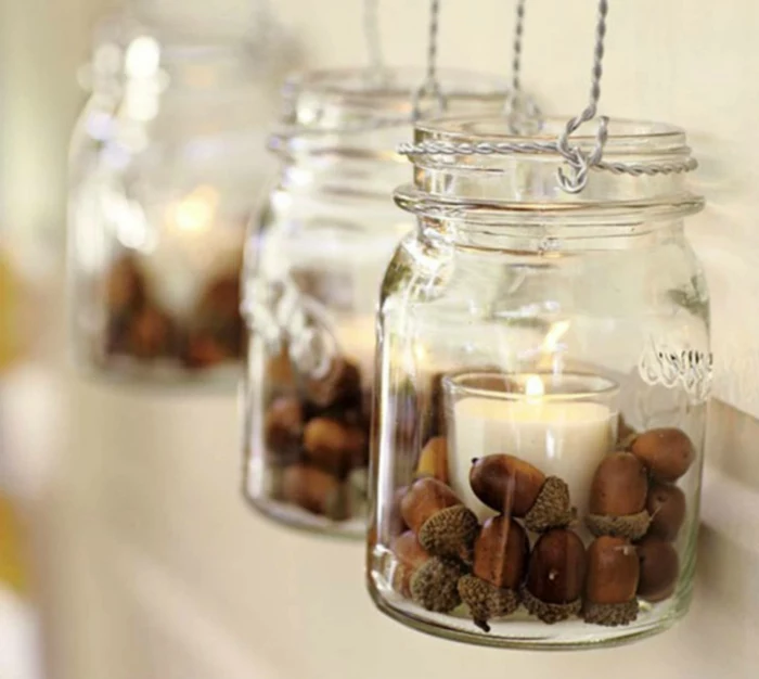 diy mason jar, three mason jars, with handles made of twisted wire, containing acorns and glasses with lit candles