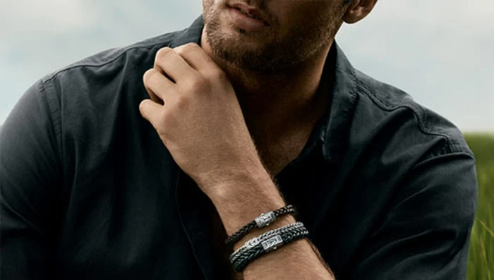 plain black casual shirt, on man with stubble, wearing three woven metal bracelets