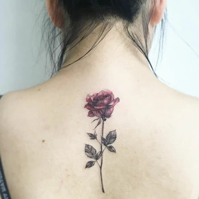 flower tattoos, close up of a woman's bare back, black hair put up, with a realistic rose tattoo, in dark pink and grey-green