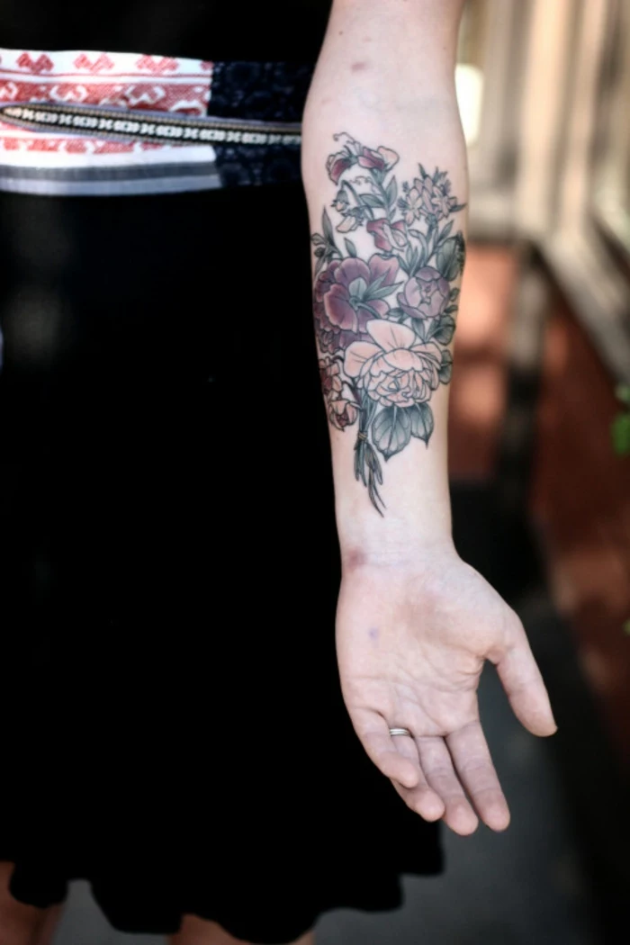botanical tattoo, outstretched female arm, with elaborate floral tattoo, with roses and other plants, with blue outlines and pale coloring, black skirt and top, with white and red in background