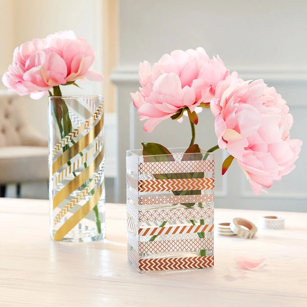 two clear vases, one round one rectangular, containing pink peonies, decorated with patterned washi tape, in gold and light brown, art and craft ideas