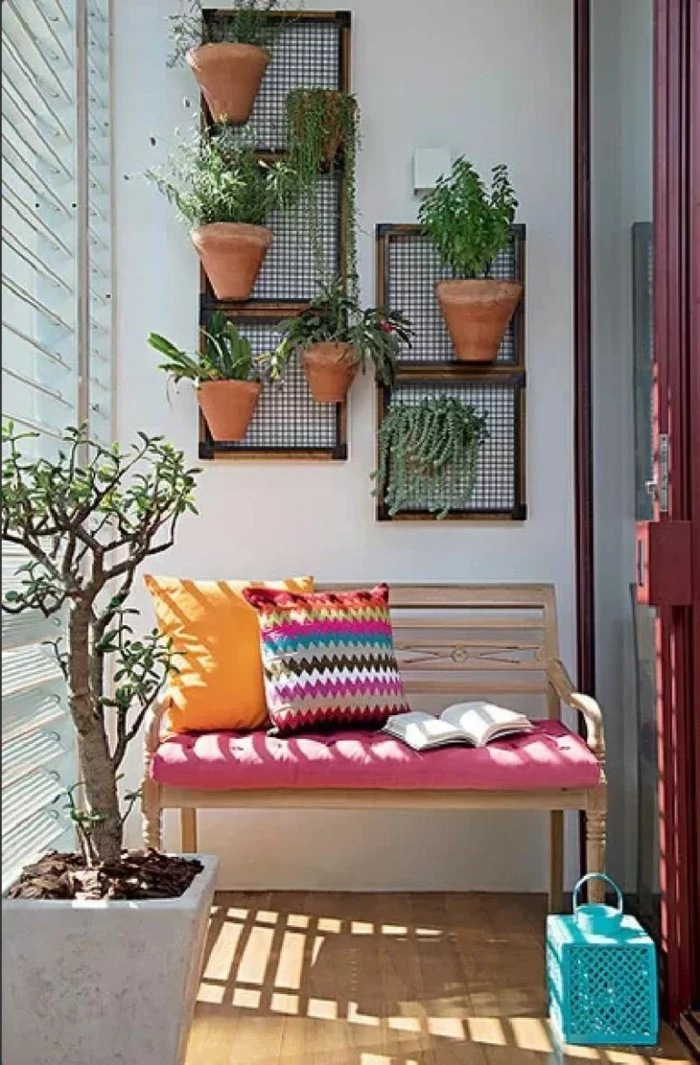 front porch décor, wooden bench with pink cover, two multicolored cushions, and a book, front porch décor, many potted plants on wall
