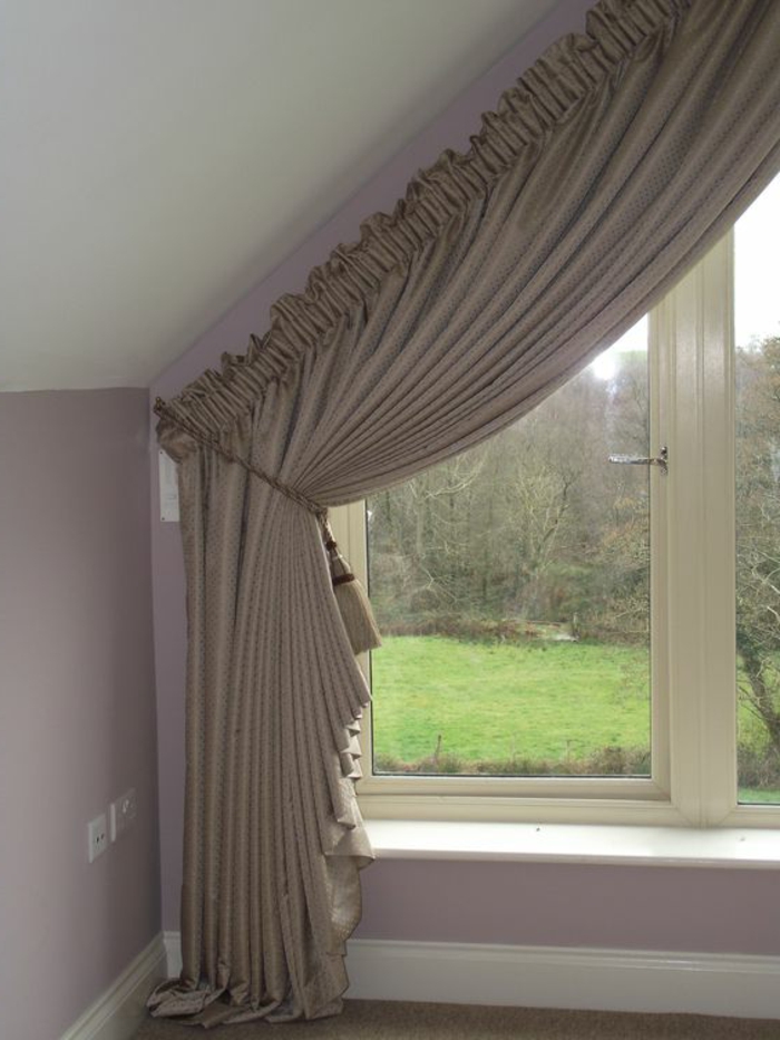 living room curtains ideas, close up of attic window, with pale brown curtain, tied with tasseled rope, pale pink wall and white ceiling