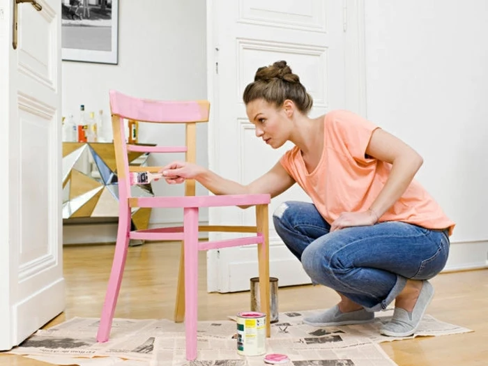 easy arts and crafts, brunette woman in jeans and t-shirt, painting a chair in pale pink, furniture and newspapers