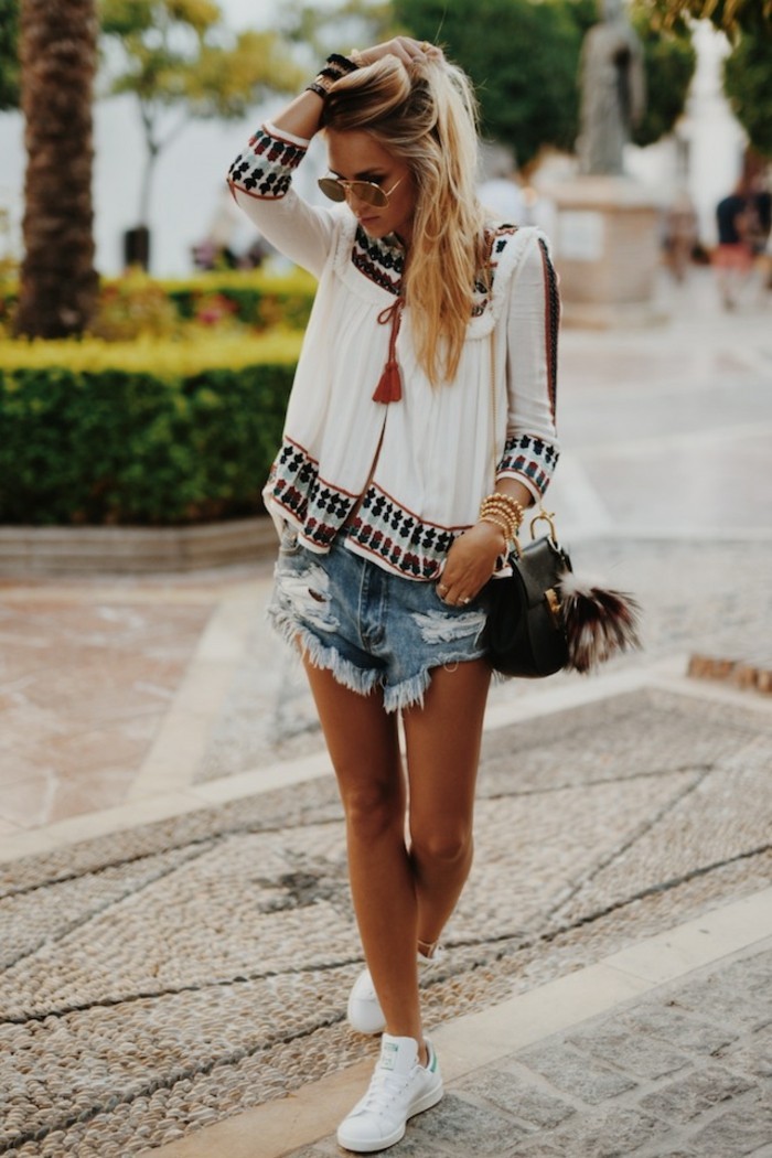 casual clothes, blonde woman with sunglasses, wearing white boho-style top, distressed and torn pale denim shorts, and white sneakers