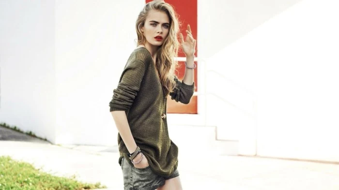 casual clothes, cara delevingne with red lipstick blond wavy hair, wearing khaki green sweater, and grey denim shorts
