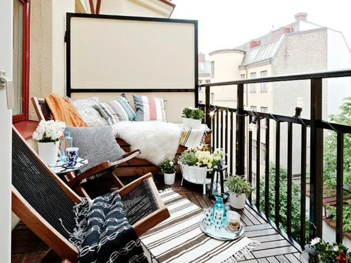two wooden lounging chairs, a wooden settee covered in throws, pillows and a white sheep skin, front porch decorating ideas, small striped rug and potted plants