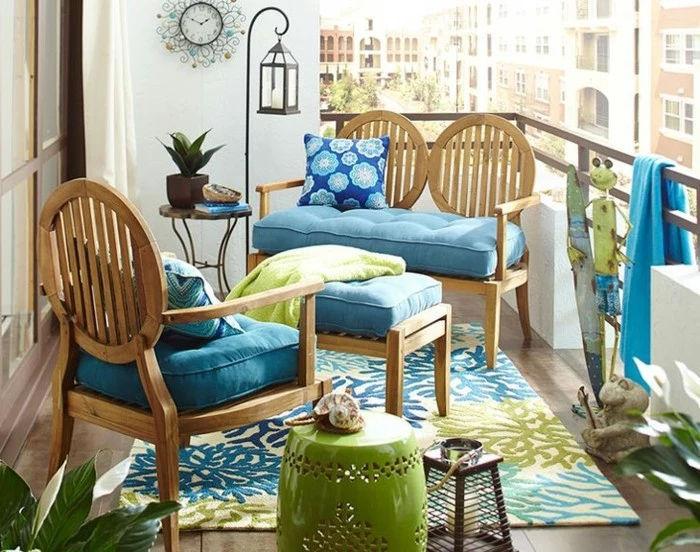 double wooden settee, with blue cover and patterned cushion, matching chair and table, porch décor, green and blue ornate rug, various decorative objects