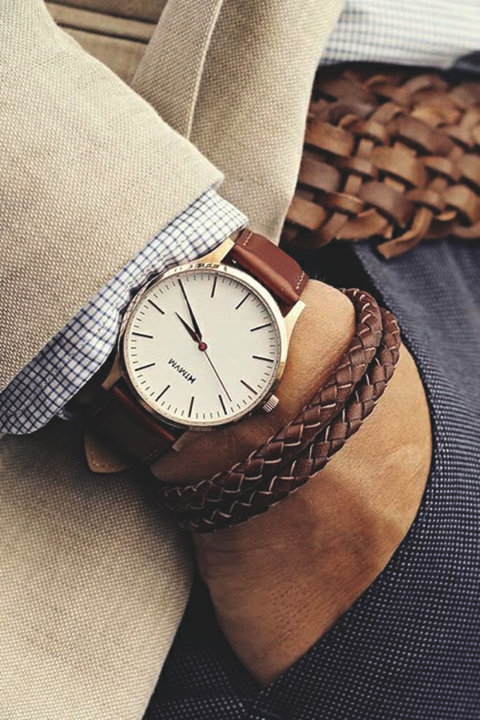 wristwatch with brown leather strap, and two woven brown leather bracelets, on the hand of a smartly-dressed businessman, business casual attire, beige blazer and chequered shirt