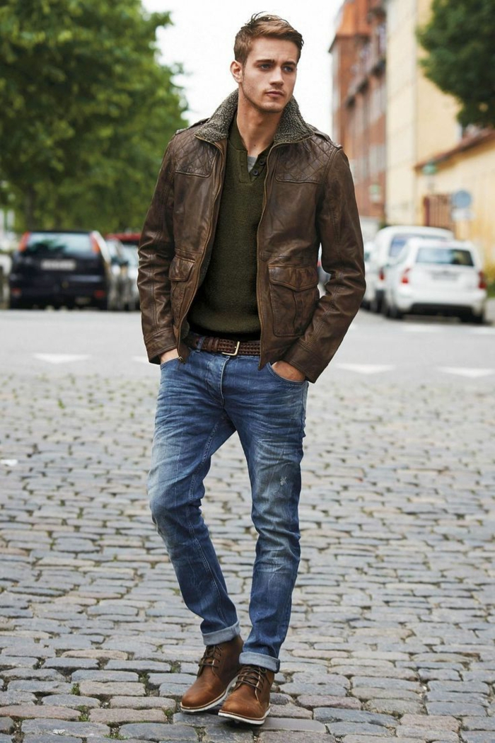 vintage-looking brown leather jacket, over khaki green jumper, casual clothes for men, combined with jeans, worn by young man, with hands in pockets