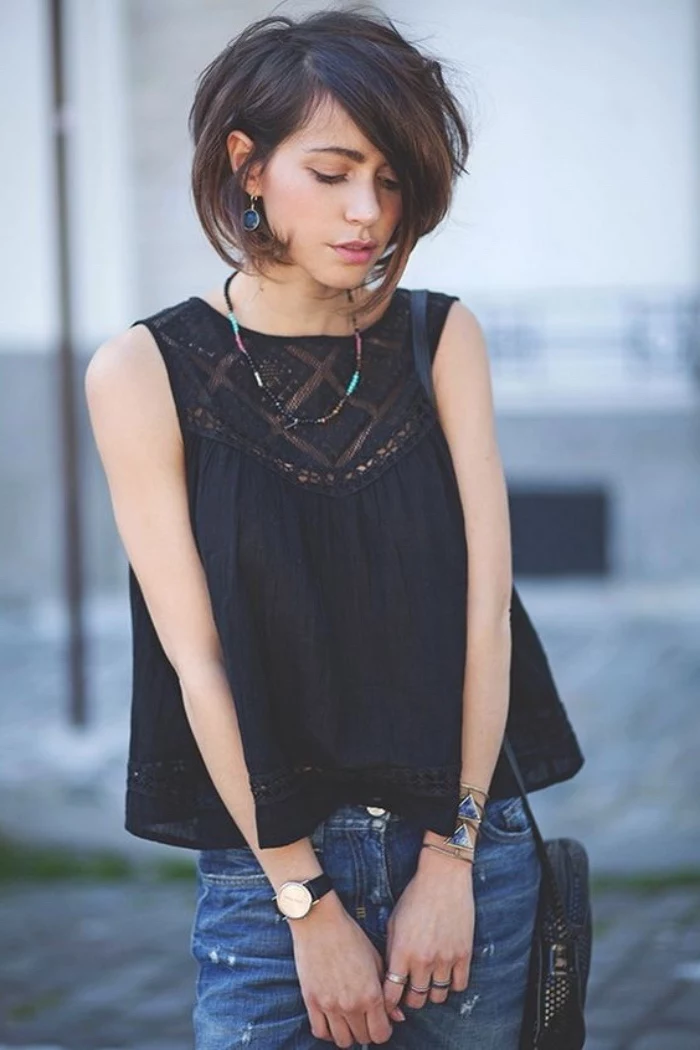 black sleeveless top, dark denim jeans, worn by young woman, with dark brunette, side-parted voluminous bob haircut