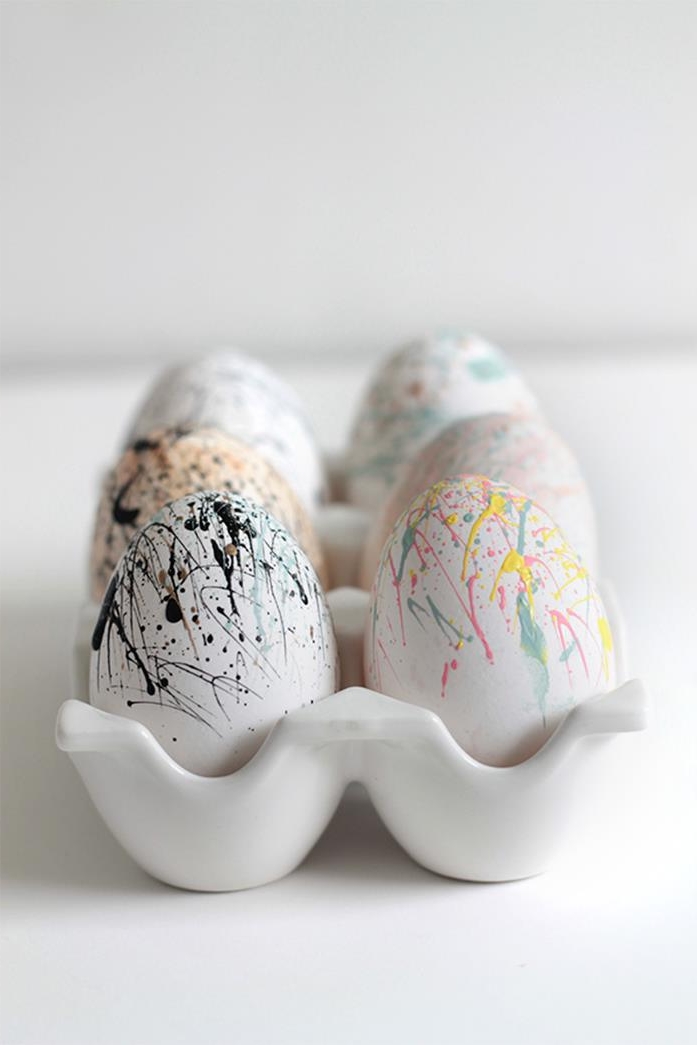 splatter of paint, either yellow, pale blue and pink, or blue brown and black, on white eggs, unusual easter idea