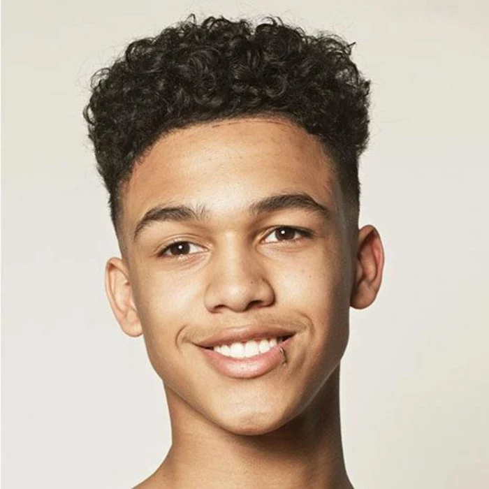 boys fade haircut, dark brown curly afro hair, on a smiling young boy, with lip piercing, disconnected undercut