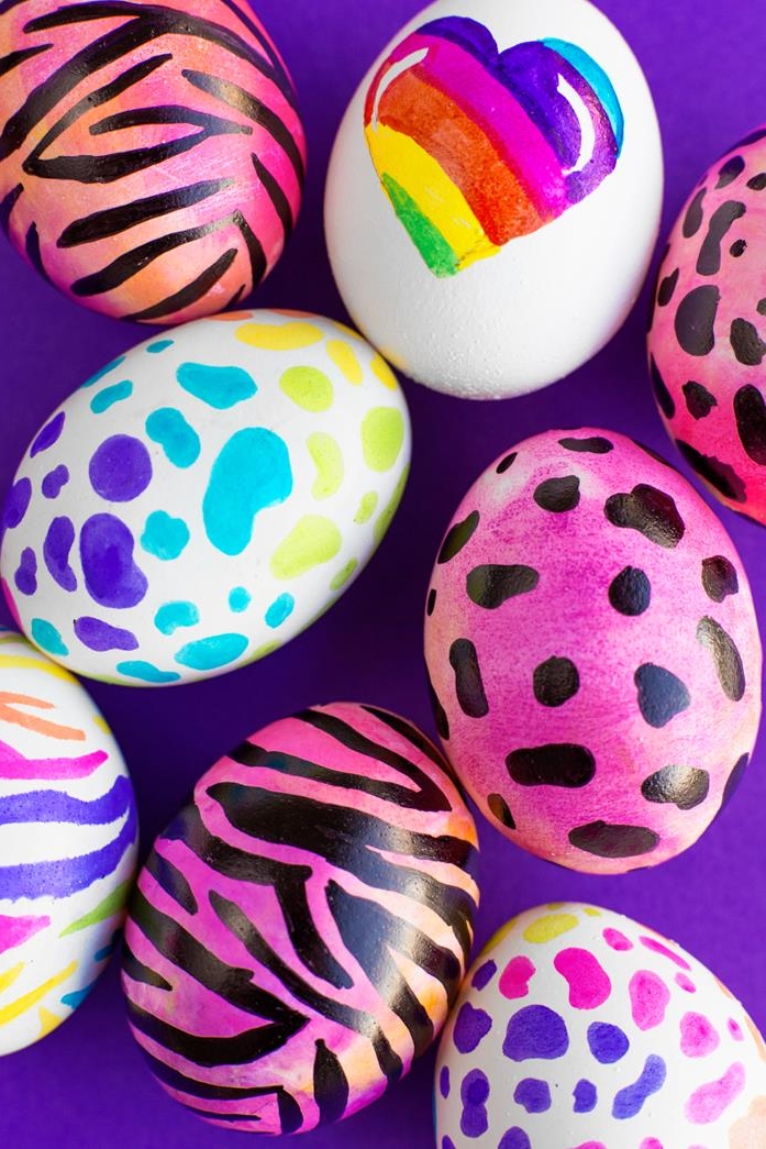 colorful eggs painted in bright neon shades, hot pink with animal print, rainbow heart on a white egg, multicolored zebra and leopard print, how to dye easter eggs, purple background