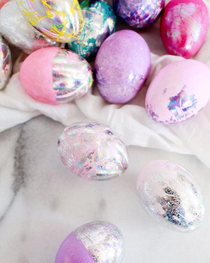 lots of easter eggs, dyed in pale and dark pink, purple and teal, silver and yellow, easter egg designs, decorated with glittering hologram paint 