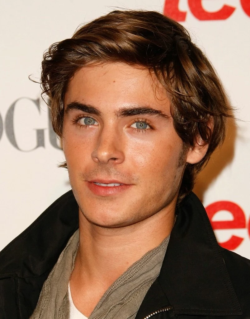 wavy tousled brunette hair, with deep side part, worn by zac efron, hair designs for boys, with scarf and winter jacket