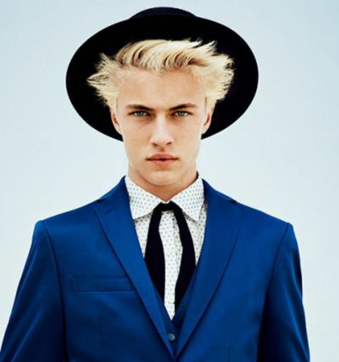big black hat, and bright blue suit, with a patterned shirt and a black tie, worn by young man, with light blonde hair, hairstyles for teenagers, rebellious look with styled up asymmetrical fringe and sides