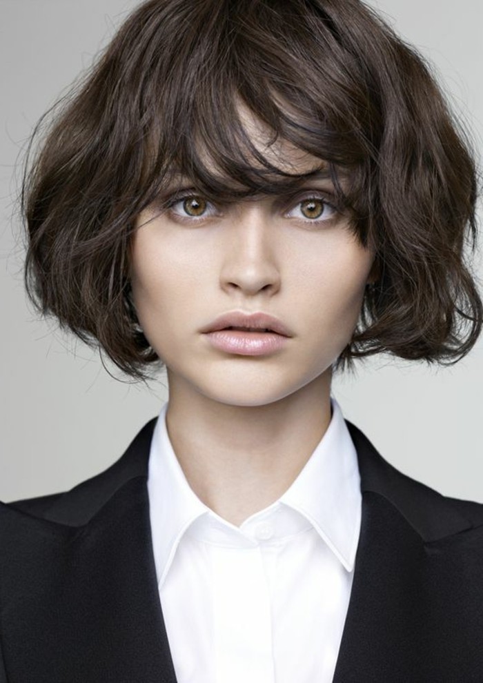 wavy bobbed hair, with messy side bangs, brunette hairstyles, worn by woman with hazel eyes, wearing white shirt and black blazer