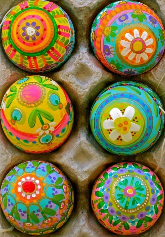 multicolored eggs painted by hand, with patterns featuring flowers and circles, easter egg ideas, placed inside a cardboard egg box