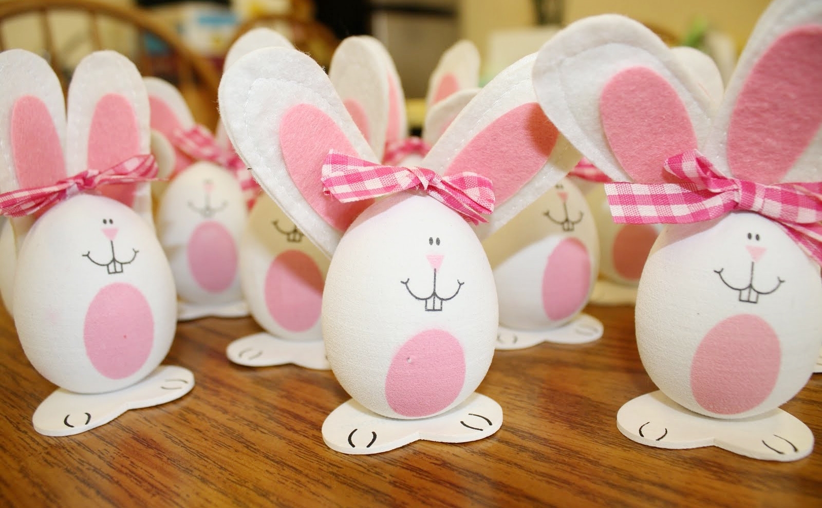 rabbits made from white eggs, easter egg designs, decorated with white and pink felt ears, fabric bows, and hand-drawn faces