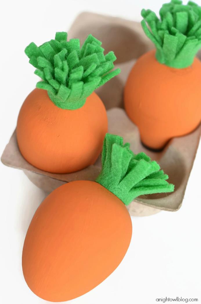 kids' easter projects, three eggs painted orange, and decorated with pieces of green felt, to make them look like carrots