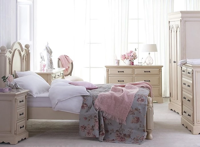 cream-colored wooden cupboards, wardrobe and bed, shabby chic decorating, white bedding with blue floral cover, and pink fluffy throw